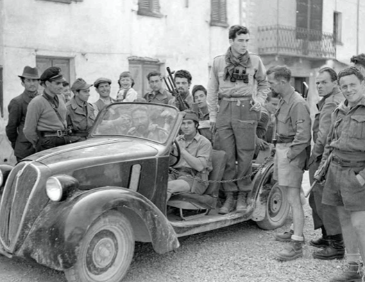 Allied soldiers and Italian partisans gathered around a car